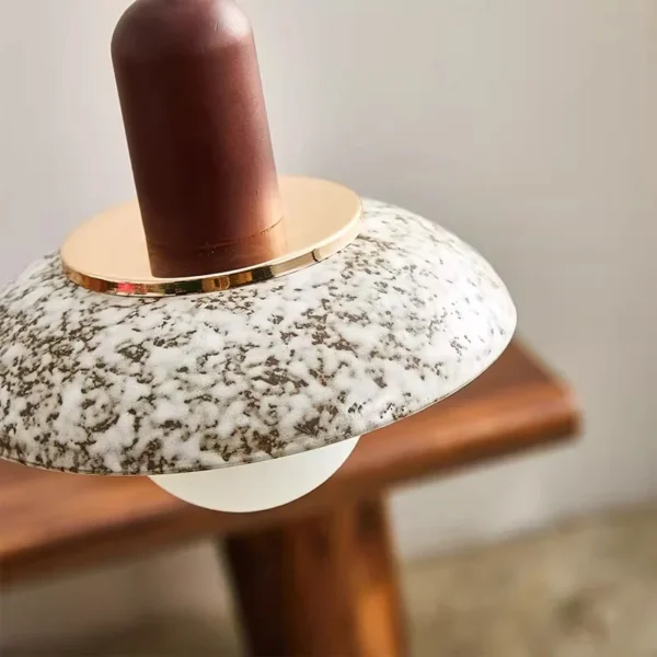 Close-up of a speckled ceramic pendant shade and wood-toned upper fitting